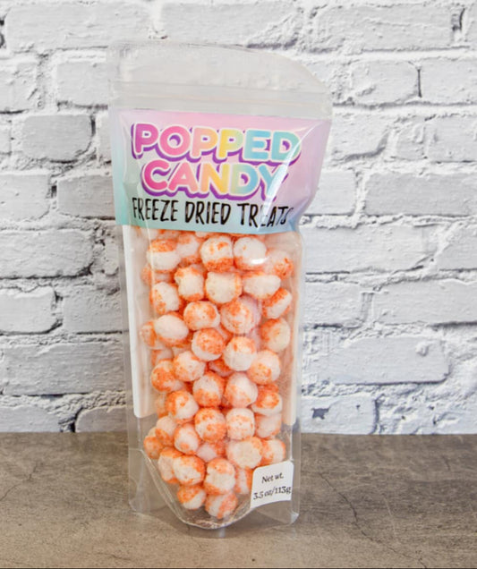 A clear plastic packaging containing freeze-dried watermelon chamoy candy bites, labeled 'Popped Candy Freeze Dried Treats' with pink and green text on a white brick background.
