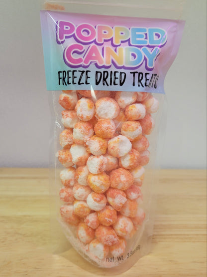 Bag of 'Popped Candy Freeze Dried Treats' on a wooden surface with a white background