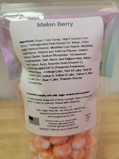 Back of a packaging with 'Melon Berry' text and ingredient list on a wooden surface.